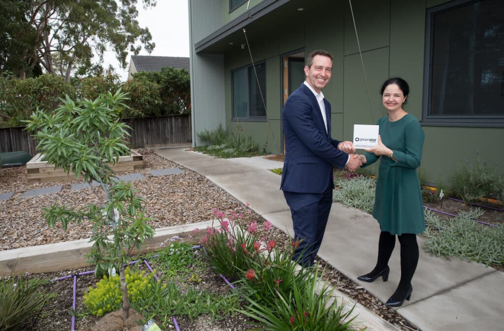 Chris Nunn and Davina Rooney shaking hands whilst holding a Green Star certified plaque.