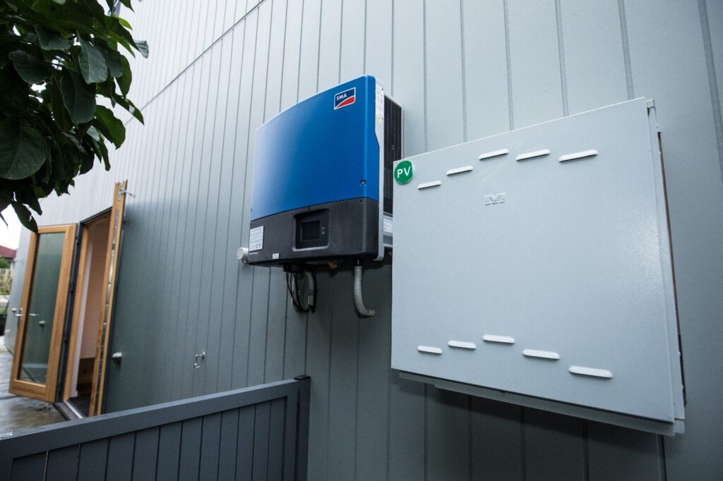 Wall-mounted solar inverter and electrical panel on the exterior of a modern building.