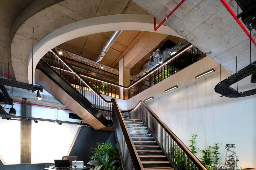 Modern industrial interior with feature staircase, exposed concrete ceiling, and steel detailing