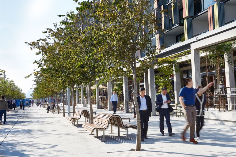 Tree-lined pedestrian boulevard at Barangaroo South with outdoor dining, retail frontage, and active public realm