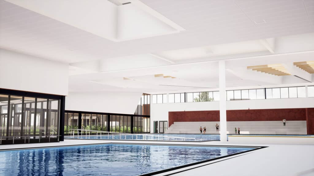 Interior of the Brimbank Aquatic and Wellness Centre pool hall featuring a large indoor swimming pool, tiered seating, and high ceilings with skylights.