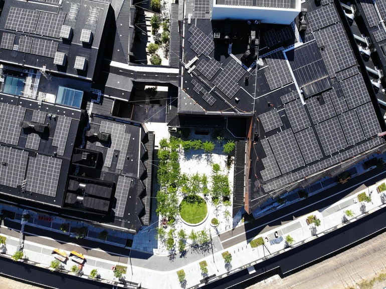 Aerial view of mixed-use precinct featuring rooftop solar panels, central courtyard, and sustainable urban design