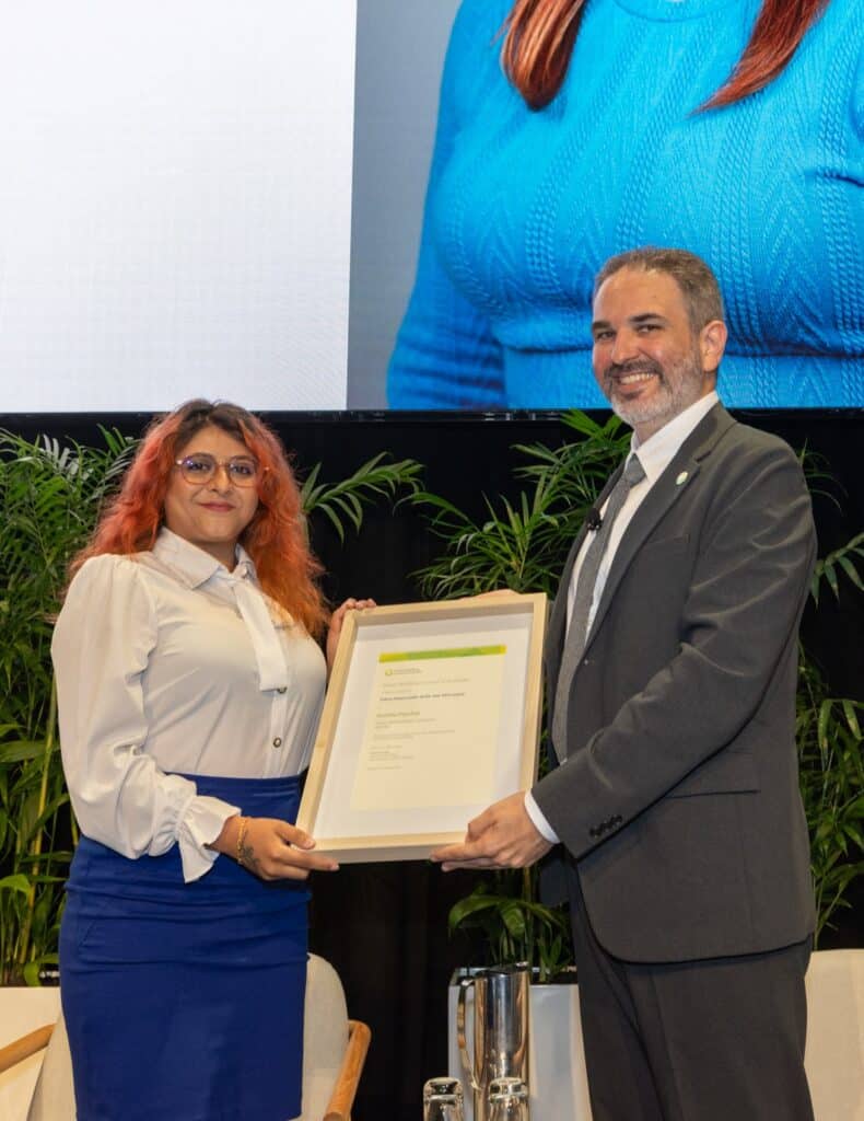 A young woman being presented an award by another man on stage at a conference