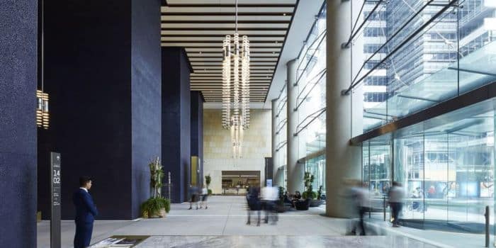 The inside of a modern corporate building lobby with a large light installment hanging from the ceiling.