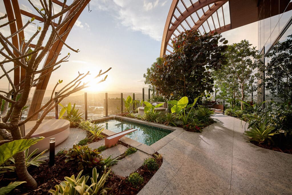 A wide shot of a private pool area on top of an apartment block balcony during sunset.