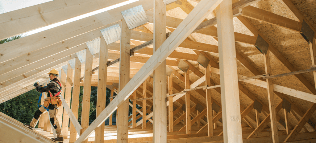A tradesman standing inside a home construction site made of timber