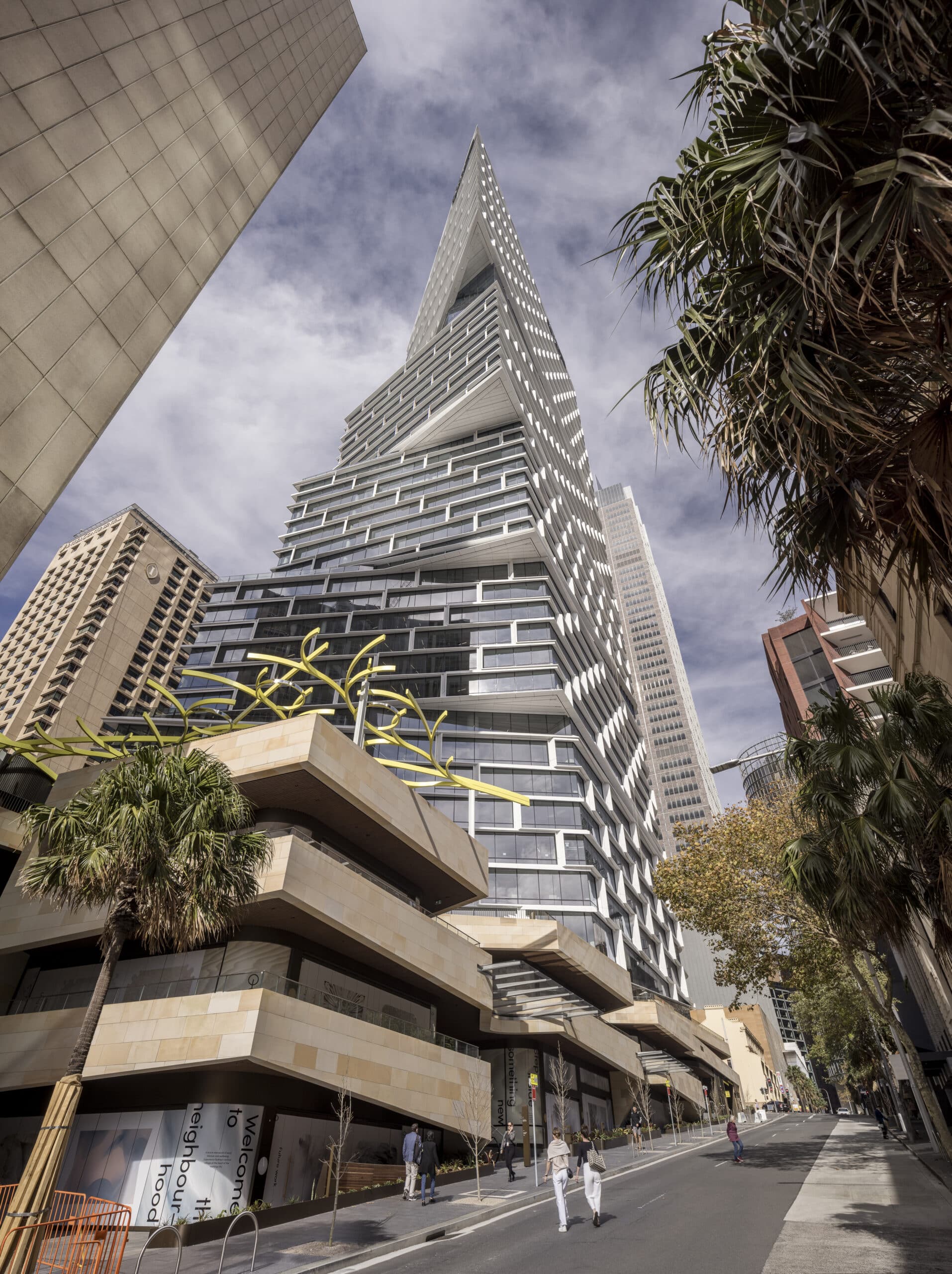 Modern Quay Quarter Tower skyscraper viewed from street level with surrounding buildings and trees.