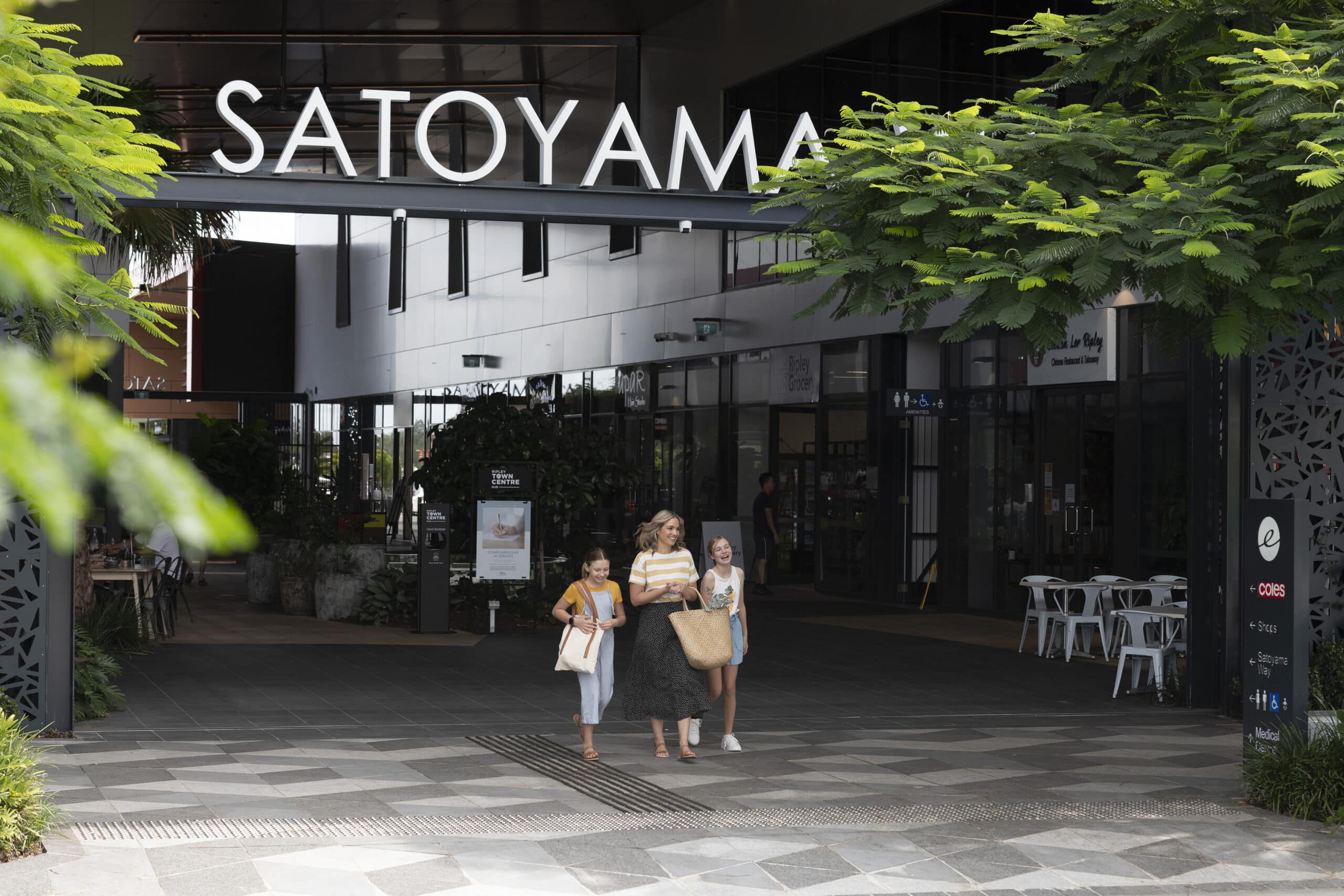 Families walking through Satoyama town centre retail precinct with landscaped greenery and outdoor dining areas