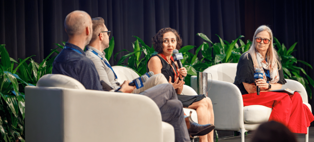 Four speakers on stage at a conference in discussion