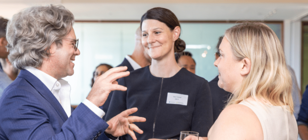 Three people engaging in a conversation and smiling at a networking event