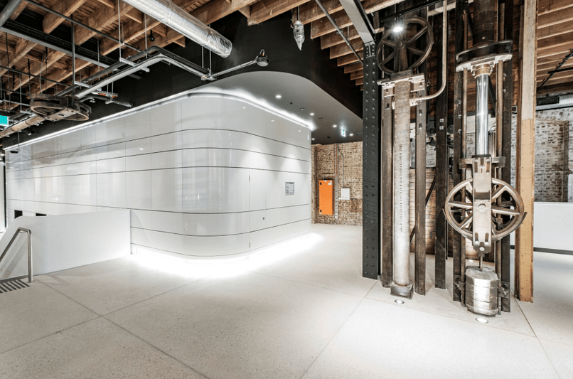 Industrial interior with exposed machinery and a sleek curved white feature in a refurbished space.